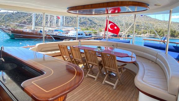 The luxurious deck of the Gulet Sahinoğlu has a large dining table, comfortable seating and a stylish bar.